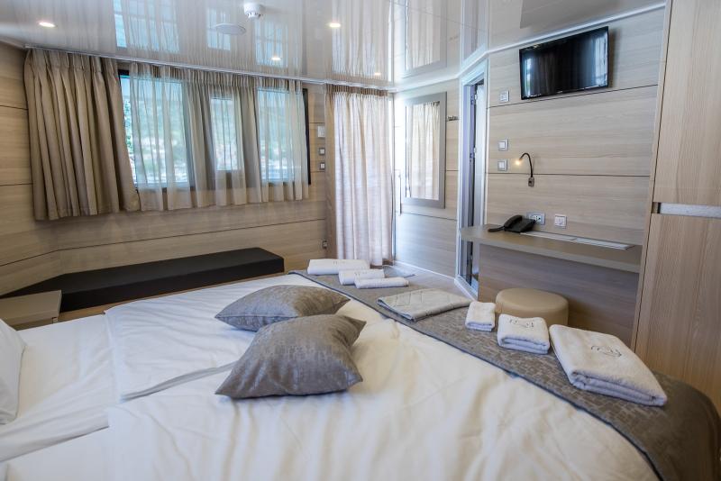 Desire Croatia Cruise ship cabin with a double bed, a small dressing table, a TV, big windows, and a private balcony.