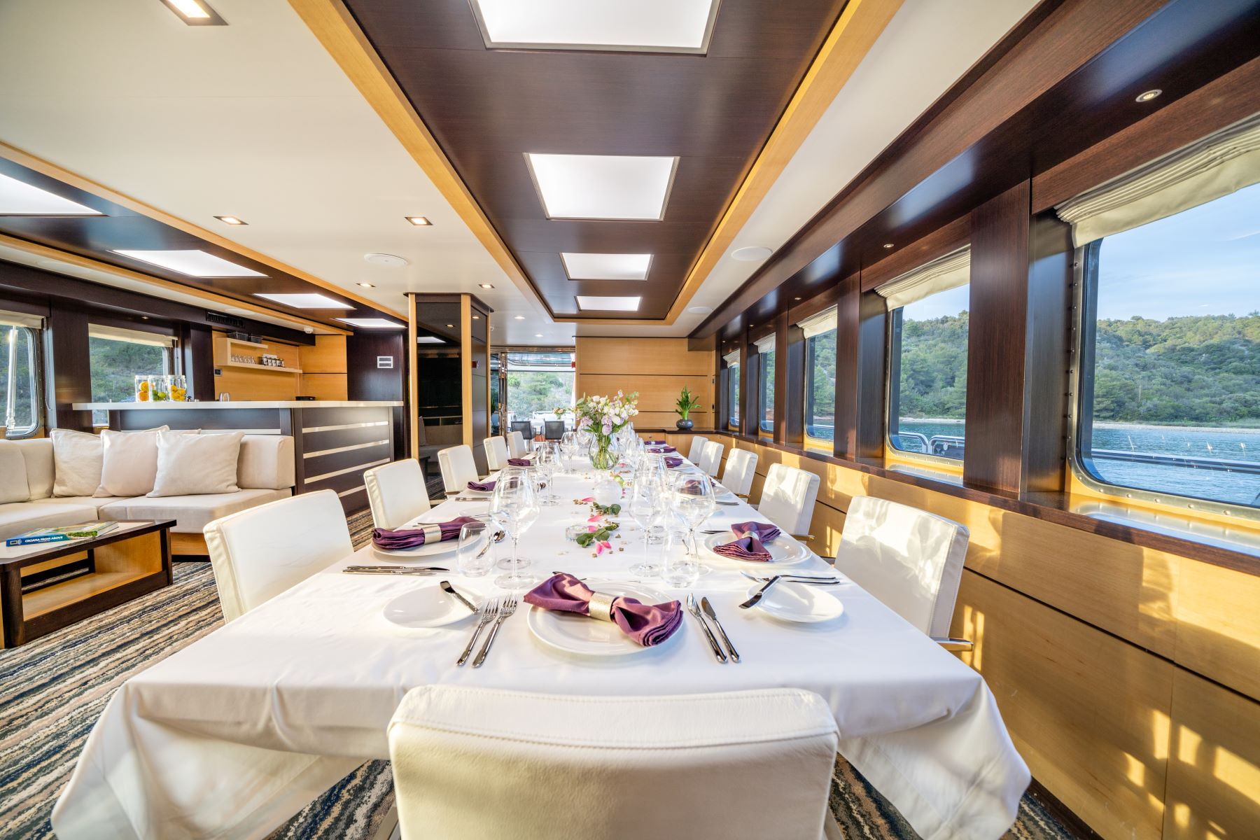 Navilux motor sailing yacht - salon, big dining area with lounge area and a bar, with big windows.