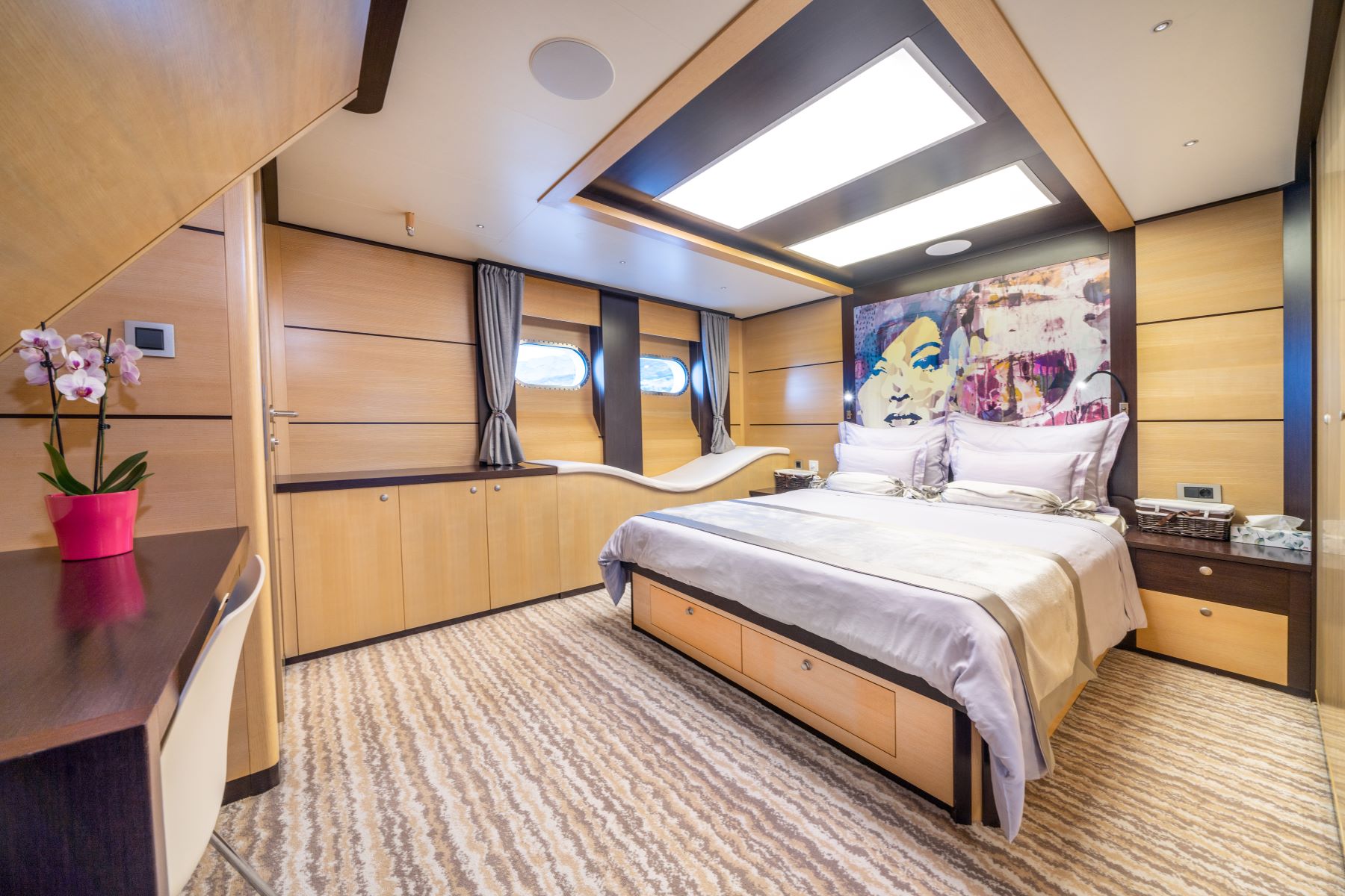 Navilux motor sailing yacht - cabin with a double bed, 2 big portholes, a dressing table, and a small lounge area.