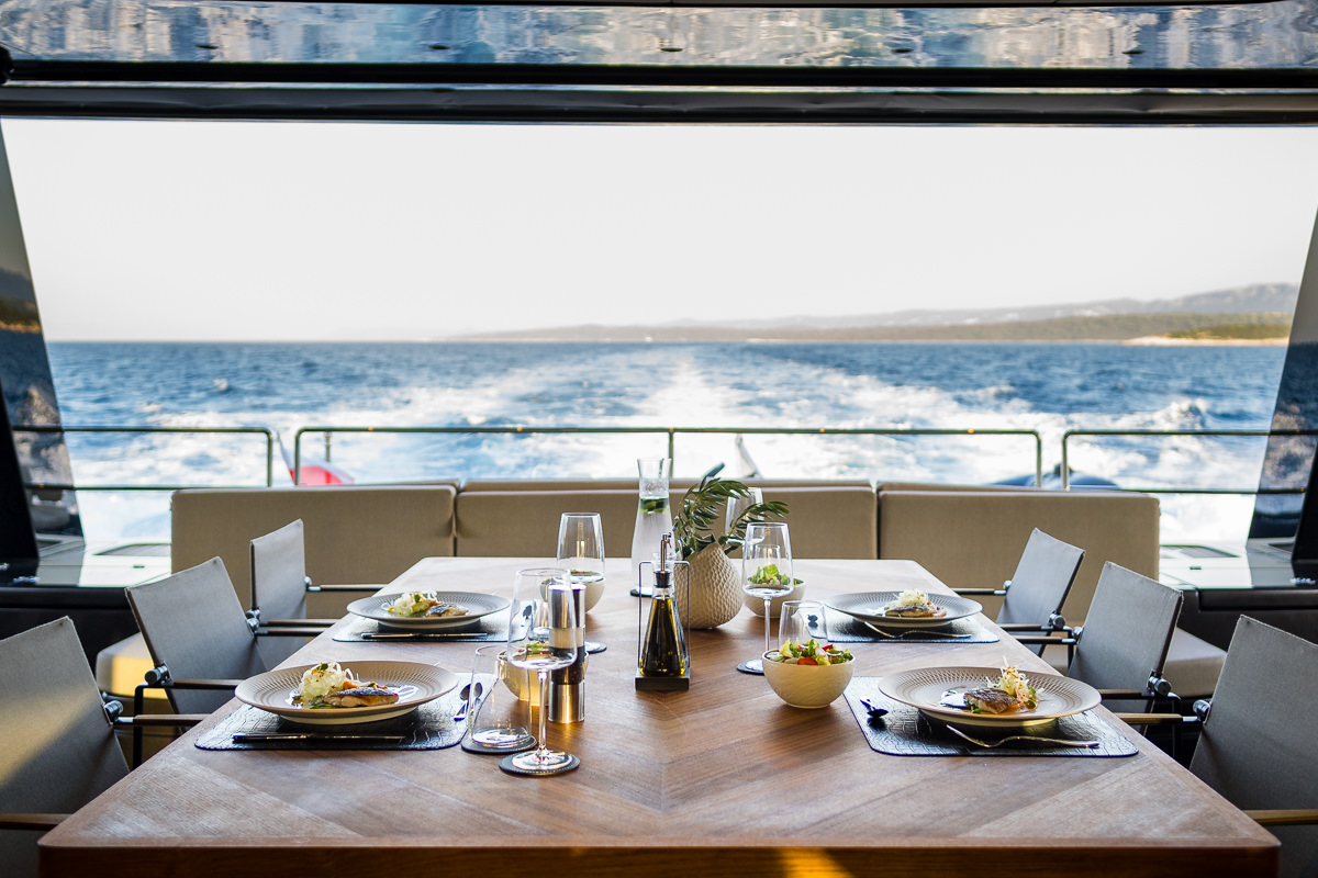 Amber One luxury catamaran - covered stern deck with a dining table and big couch.