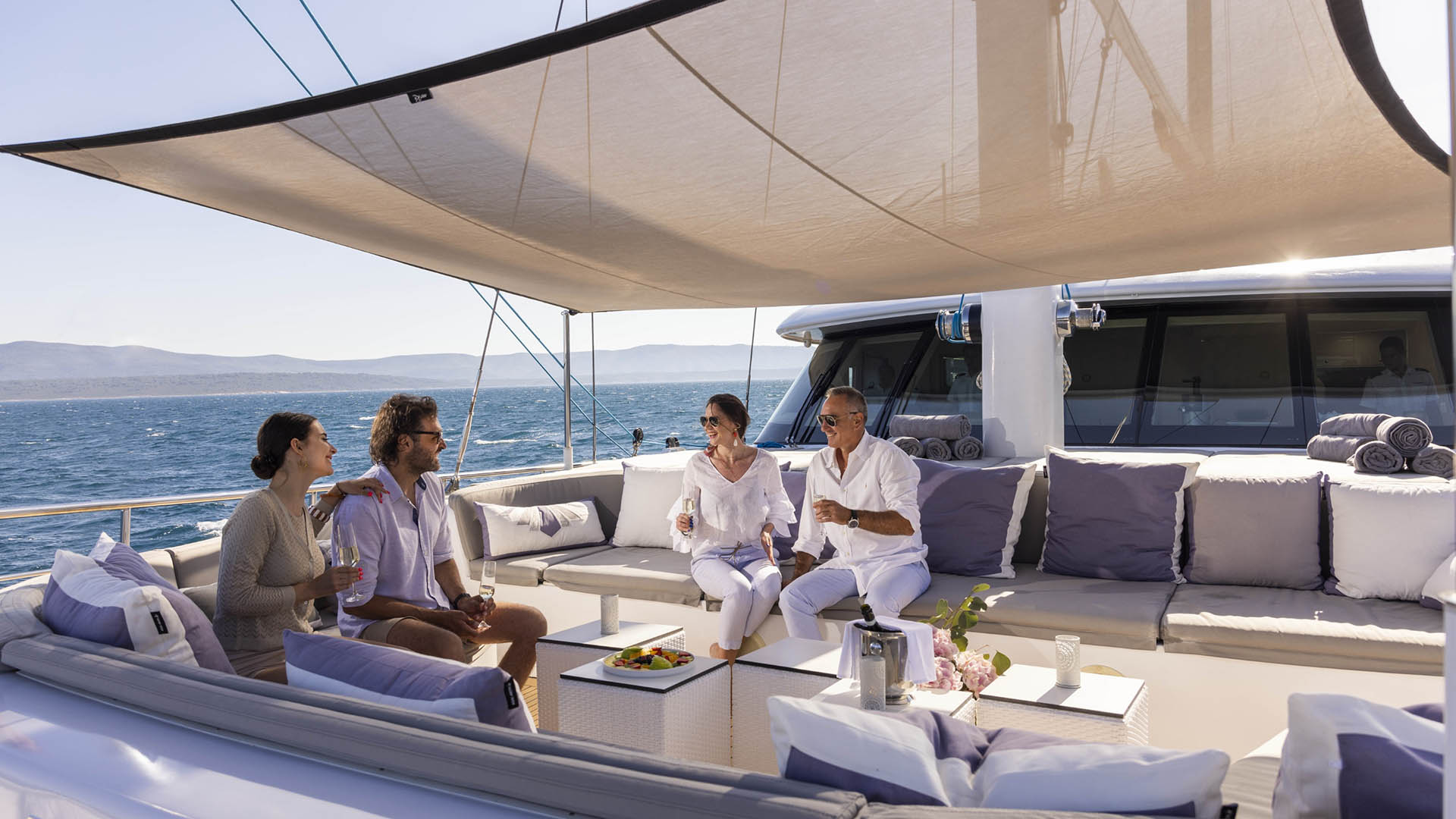 Aurum Sky sailing yacht - 2 couples enjoying drinks in the lounge area on the main deck bow.