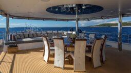 Aurum Sky sailing yacht - covered outdoor dining area on the main deck stern with a big lounge area behind it.