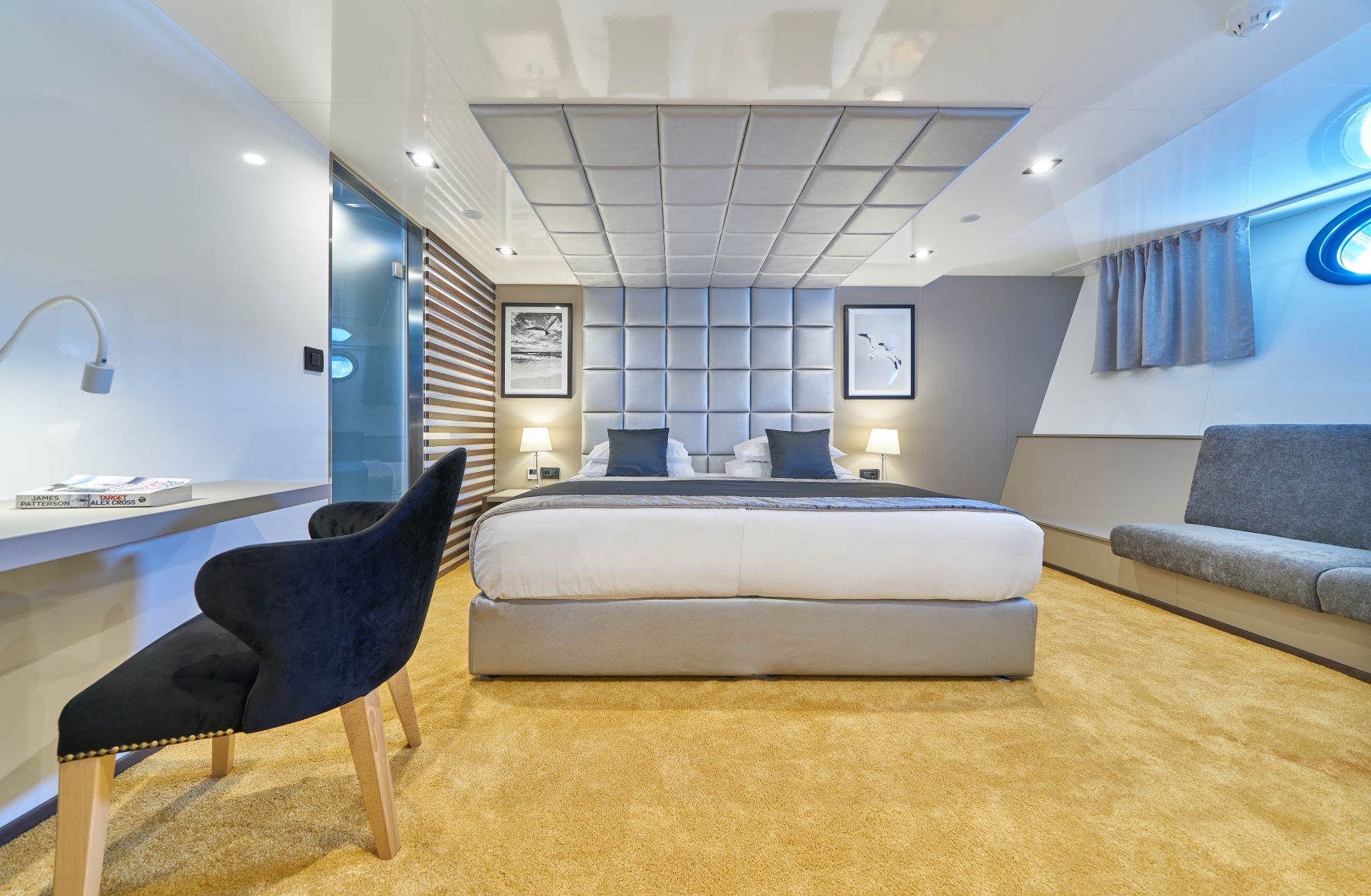 Rara Avis sailing yacht - cabin with a double bed, sofa, porthole, dressing table, and an ensuite bathroom.