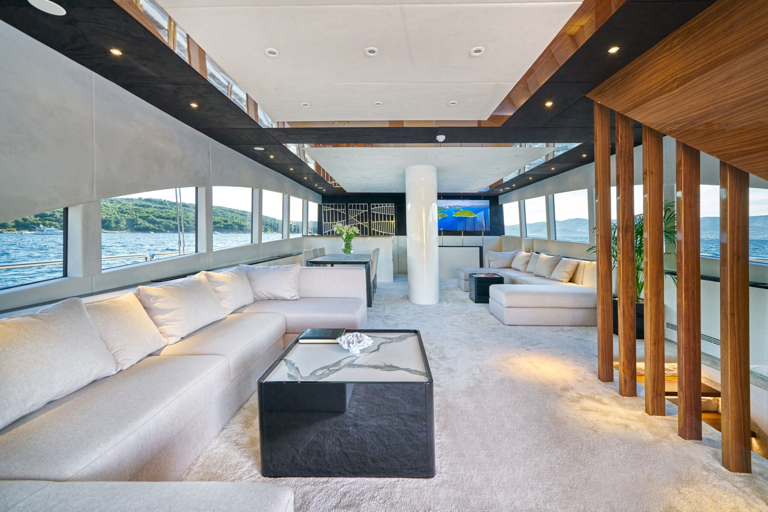 Acapella luxury charter yacht salon with 2 big lounge areas, stairs for cabins, and big window surfaces.