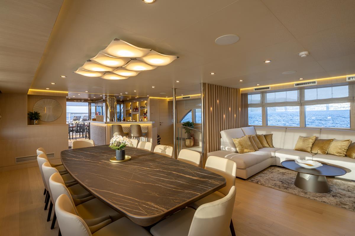 Love Story's luxurious sailing yacht salon - dining table, lounge area, a bar and big windows.