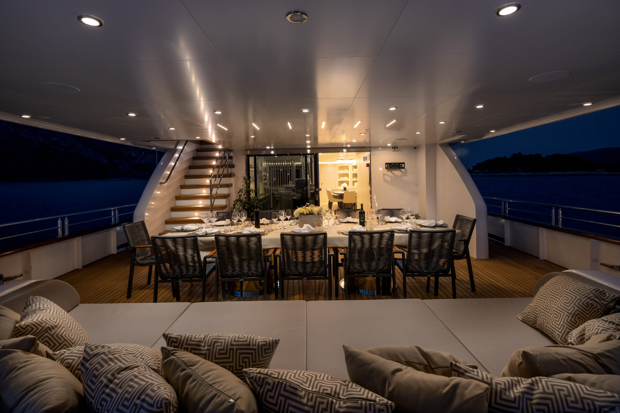 Love Story's luxurious sailing yacht stern deck - lounge area, dining table, and stairs for the upper deck and entrance to the salon.
