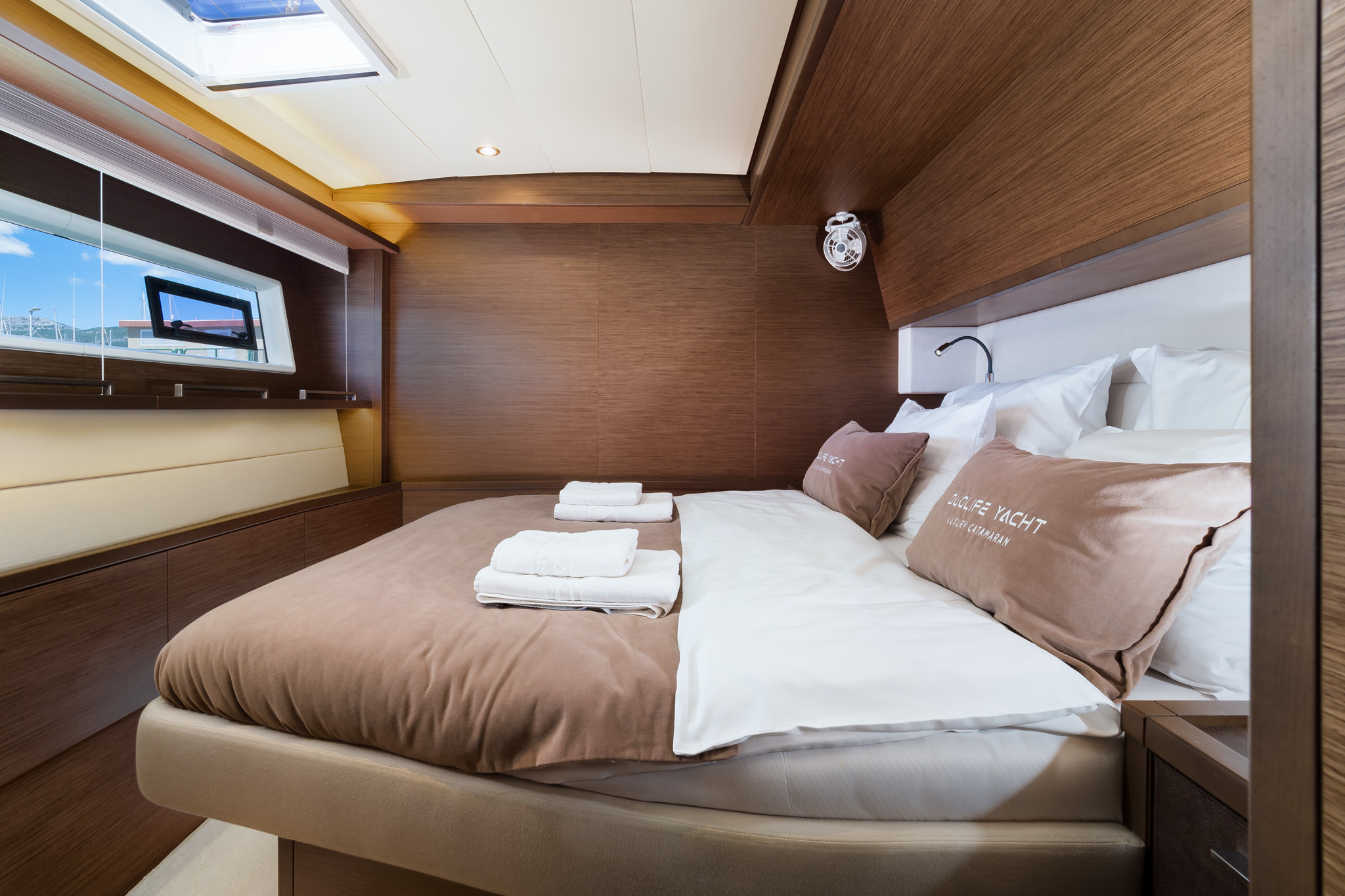 Luxury yacht Duolife catamaran double bed cabin with big window and a porthole - with a nice wooden interior.
