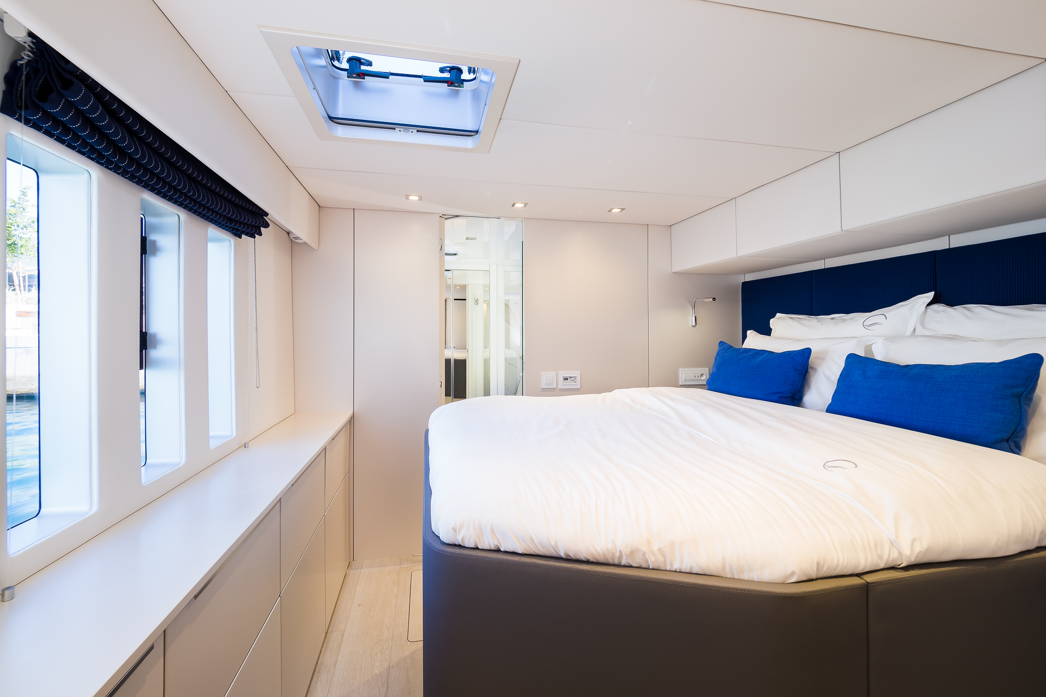 Luxury yacht Solitaire catamaran double bed ensuite cabin with 3 big windows and a porthole and opened door of the bathroom