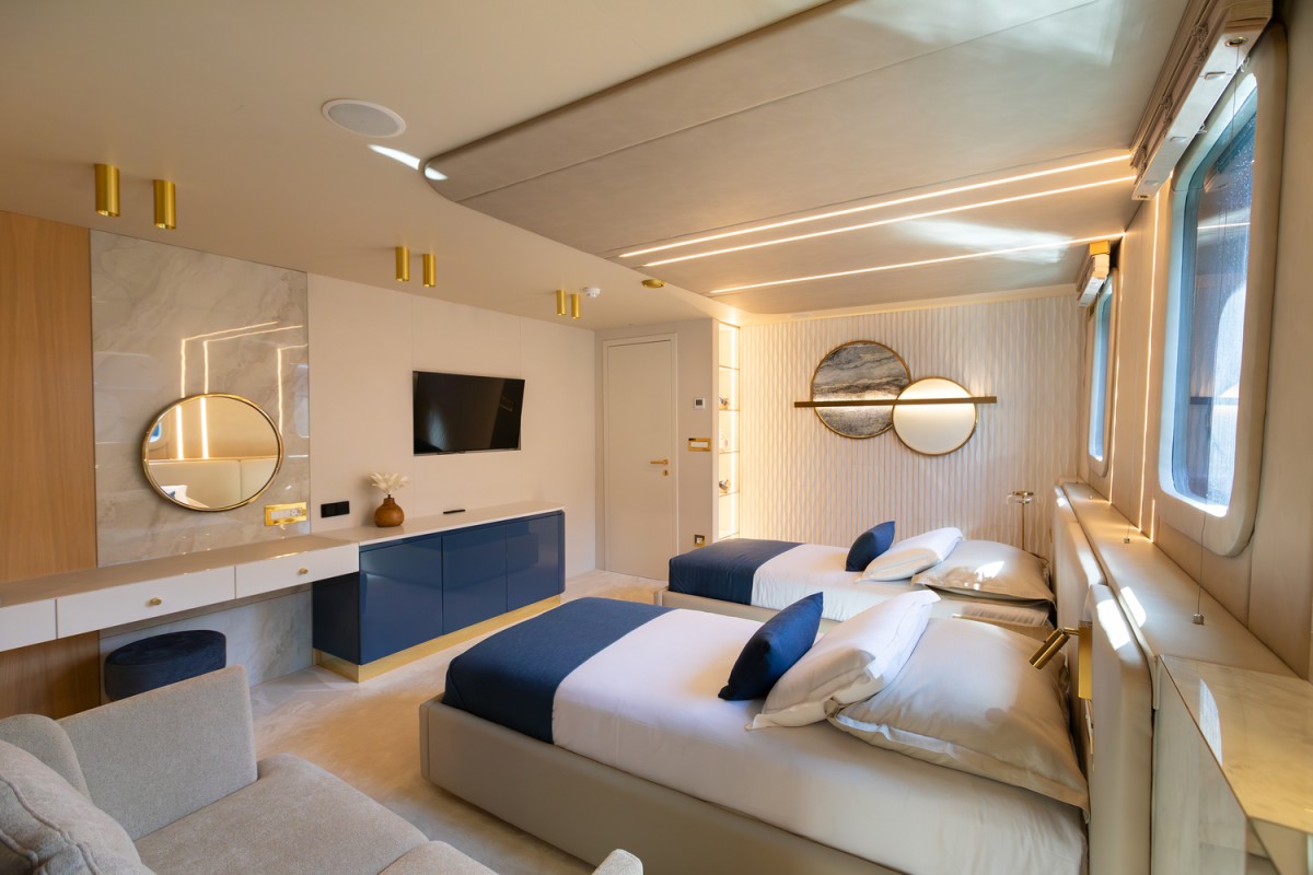 Cabin with 2 single beds, 2 big windows, sofa, dressing table, and a TV on the Scorpios sailing yacht.